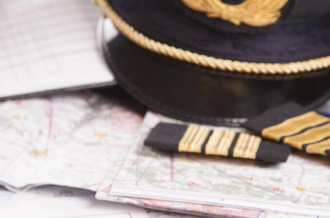 Pilotenmütze liegt auf Flugkarten
